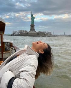 a woman looking up at the statue of liberty in new york city on a boat