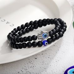 This beautiful 6cm Black Glass White Turquoise Colored Glaze Beaded Devil's Eye Bracelet Set is the perfect gift for your special someone. This gorgeous set includes a beaded bracelet made with natural black glass and white turquoise beads, perfect for any occasion. The unique design is a statement piece that adds an elegant touch to any outfit. Not only that, but this minimalist bracelet is highly customizable, making it the perfect gift for a girlfriend, wife, daughter, mother, sister, aunt, o Black Evil Eye Bracelet With 8mm Beads For Gift, Black Evil Eye Bracelet With 8mm Beads As Gift, Gift Round Black Beaded Bracelets, Black Beads Bracelet Wristband Gift, Black Beads Wristband As Gift, Beaded Bracelets With Black Beads For Gifts, Gift Beaded Bracelet With Black Beads, Round Black Beaded Bracelet As Gift, Black Beaded Wristband As Gift