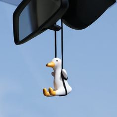 a duck hanging from the side mirror of a car in front of a blue sky