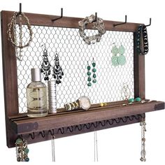 a wooden shelf with jewelry hanging from it's sides and a bottle on top