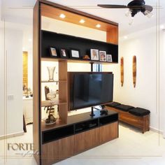 a living room with an entertainment center in the middle and a ceiling fan above it