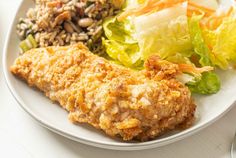 a white plate topped with fried chicken, salad and rice