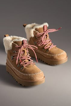 Rooted in UGG® heritage, this boot showcases iconic features like the curly sheepskin collar, UGGplush lining, and smooth suede upper. Round laces and Heritage Twin Seam details give this booth depth, while the lug sole provides traction for those first-snowfall walks. | Classic Alpine Lace-Up Boots by UGG in Beige, Women's, Size: 7, Polyester/Leather/Wool at Anthropologie Cute Winter Boots, Ugg Snow Boots, Bow Boots, Shoe Inspo, Ugg Classic, Womens Ankle Boots, Winter Shoes, Fashion Books, Lug Sole