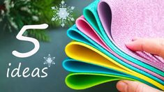 a hand is holding several colored papers with snowflakes on them and the words 5 holiday ideas written in white