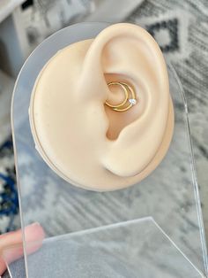 a close up of a person's hand holding a fake ear with a ring on it