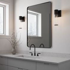 a bathroom sink with a large mirror above it and lights on the wall behind it