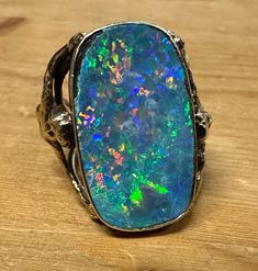 Details:This STUNNING & Absoilutely Custom Unique 1 of 1 MASSIVE 16+ carat  Black Opal 18k Yellow Gold Statement Ring is a museum quality rarity! The ring features a rainbow cascade of color in the giant black opal stone upheld by two intertwined sirens, one on each side of the band. The ring displays wear from daily use to the gold and heavy wear to the opal such as chips and heavy crazing (see photos). The cascade of colors in this opal are absolutely mesmerizing and not done justice by photo or video. The gold is not hallmarked but acid tested for 18k. This is a true 1 of 1, once in a lifetime piece. This is befitting as a true collection completion piece. It is extraordinary in every sense of the word. What you see pictured here is what you will be receiving. This listing is for the RI