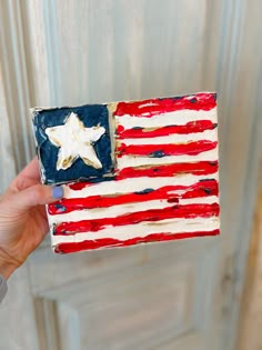 someone holding up a cake decorated with an american flag