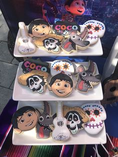 three tiered trays with decorated cookies on top of each other in the shape of cartoon characters