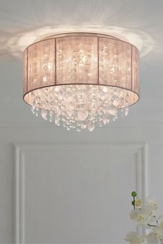 a chandelier hanging from the ceiling in a room with white walls and flowers