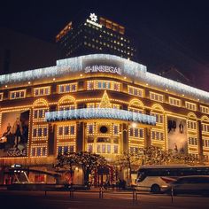 a large building with christmas lights on it's side and cars parked in front