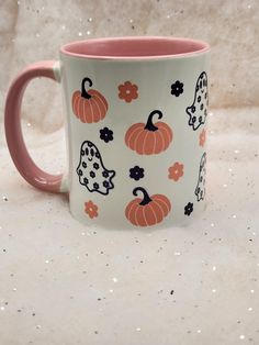 a pink and white coffee mug with halloween decorations on it