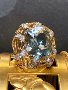 Now this ring is fabulously made. It is done in 18K yellow and white gold and centered by an approximately 20ct cushion cut aquamarine (17.82x15.58x10.18). Bead set down all sides of the ring are incredibly well matched collection quality diamonds ranging F-G in color and Vs1+ clarity with a total approximate weight of 3.10cttw. This is a true showstopper. Dimensions/Weight: Ring measures 1.1" by 1" and weighs 22.2g. Size 5.5 with sizing guard but the ring is sizable by quite a bit. Condition: A Luxury Gold Aquamarine Rings, Bead Set, Beautiful House, Quality Diamonds, Cocktail Ring, Cushion Cut, Cocktail Rings, Rings Statement, Aquamarine