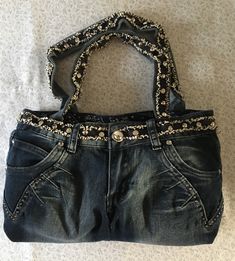 This jean purse is beautifully garnished with silver brades and eye catching glass button. The band and handle straps are covered with dark blue raveled trim with large silver and glass brades. The back pockets are garnished with rows of five star glass gems. The purse is fully lined with western blue handkerchief fabric with two inside pockets. The purse has a Velcro fascine. the size of the purse is 16 inches wide and 9 inches tall. How To Make A Purse Out Of Jeans, Jean Pocket Purse, Purse Aesthetic, Blue Handkerchief, Jean Bag, Jean Purses, Denim Crafts Diy, Fashion Jobs, Jean Purse