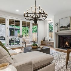 a living room filled with furniture and a fire place under a chandelier in front of a fireplace