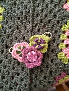 two crocheted flowers sitting on top of a blanket