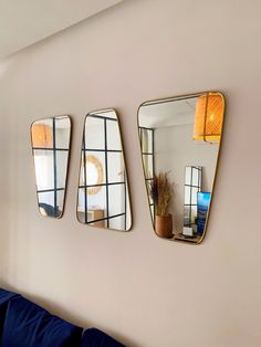 three mirrors are hanging on the wall above a blue couch in a living room area