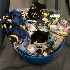 a batman themed gift basket is sitting on a bed with the contents wrapped up and ready to be eaten