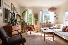 a living room filled with furniture and lots of plants on the windows sill in front of them