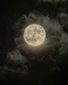 the full moon is seen through some clouds