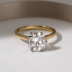 a gold ring with a round diamond on the side and a beige ribbon around it