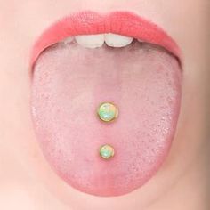 a woman's tongue with two gold studs on it