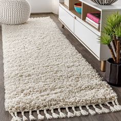 a large white rug with tassels on the floor in a living room area