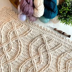 three balls of yarn sitting on top of a table next to crochet hooks