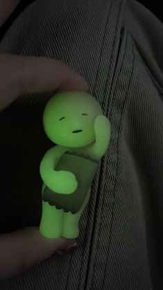 a person is holding a green glow in the dark stuffed animal on their left hand