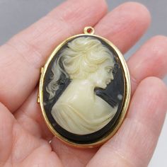 *Description: This is a great pendant locket with a Lucite cameo in black and creamy white from the 1960s. The Victorian lady's profile is on the top with a hidden locket inside. The locket will hold up to two photos. The locket pendant cameo is ready for you to add your own chain and favorite photos. It would also make a great gift. *Approximate Measurements: Length - 2 Inches, Width - 1 3/8 Inches, Weight - .7 Ounces *Condition: Great vintage condition. You will see signs of wear. There is no Vintage Cameo Pendant Locket Necklace, Vintage Black Locket Necklace, Pendant Locket, Victorian Lady, 1960s Vintage, Creamy White, Locket, Hold On, Vintage Jewelry