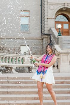 a woman standing in front of a fountain spraying water