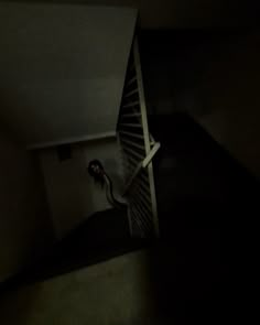 a person is walking up the stairs in an empty room at night time with their feet on the railing