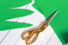 a pair of gold scissors sitting on top of a green piece of felt next to cut outs