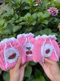 three pink knitted baby booties with cherries on them