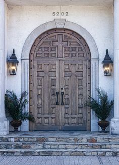 an entrance to a building with two large wooden doors and planters on the steps