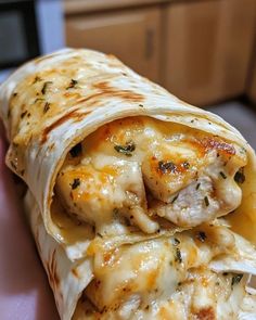 a close up of a burrito on a plate with cheese and chicken in it