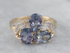 "This tanzanite band is feminine and elegant! The purplish-blue of the stones pairs perfectly with the gold band, while the white sapphires add a pop of light that enhances the sparkle of the tanzanites. This ring would stack well with other bands! Metal: 10K Yellow and White Gold Gem: 3 Tanzanites totaling 1.95 Carats Gem Measurements: 5 x 7 mm, Oval Accents: 8 White Sapphires totaling .07 Carats Ring Size: 8.25 Marks: \"CR 375\" Stamped on the inside band SKU #: 2DU3L7JZ Each piece has been id Sapphire Gold Ring, Sapphire Diamond Pendant, Gold Diamond Band, Tanzanite Ring, Blue Sapphire Diamond, Halo Pendant, Purple Band, Diamond Anniversary, December Birthstone