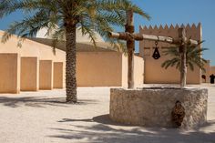 a palm tree in front of a building with bells hanging from it's roof