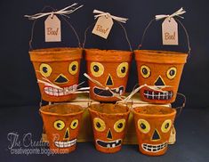 five halloween buckets with faces painted on them and tags attached to the top one