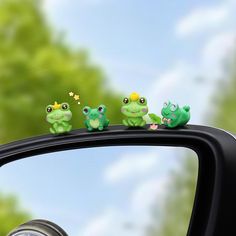 the frog family is sitting on top of the car's side mirror, looking out the window