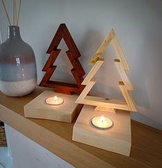 two wooden candles are on a shelf next to a glass vase and candle holder that is shaped like a christmas tree