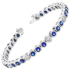 This stylish and elegant tennis bracelet features over 6 carats of blue sapphires and over 2 carats of white diamonds, with each gem showcased in its own 18k white gold bezel. The sapphires have extraordinarily fine color and are beautifully matched, making this bracelet quite a collection of gems! Sparkling round diamonds are the perfect complement to sapphires of this quality - a classic combination, while the bezel setting adds an updated look to a timeless design. The clasp includes a hidden Modern Bracelets, Blue Sapphire Diamond, Gold Art Deco, Tennis Bracelet Diamond, Bezel Diamond, Quality Diamonds, Tennis Bracelet, White Diamonds, Round Brilliant Cut Diamond