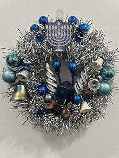 a hanukkah wreath with blue and silver ornaments hanging on a white wall