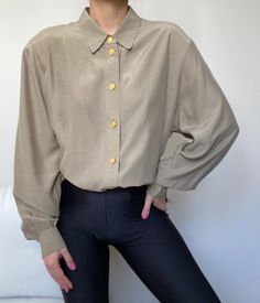 A beautiful neutral shirt with gold buttons and removable shoulder pads.  Looks great worn as a shirt or a tunic, depending on your height. Mint condition. Composition: cupro , viscose Size : S-XL depending on the desired drape. Our model is size XS/S and the shirt is not pinned on her. Note: If you have any additional questions about the sizing and measurements of the items, please DM me! *all items have been professionally cleaned and ready to wear! Most of the items are vintage and therefore Gold Long Sleeve Tops With Buttons, Beige Button-up Top With Button Cuffs, Gold Button-up Top For Workwear, Gold Button-up Top For Work, Gold Long Sleeve Shirt With Buttons, Gold Collared Blouse For Work, Gold Long Sleeve Tops With Button Cuffs, Chic Gold Top With Button Closure, Chic Gold Tops With Button Closure