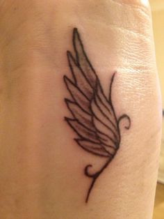 a small tattoo on the wrist of a woman's left arm with a bird design