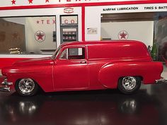 a red car is parked in front of a gas station