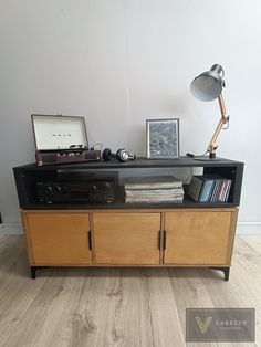 an old record player is sitting on top of a wooden entertainment center with books and records