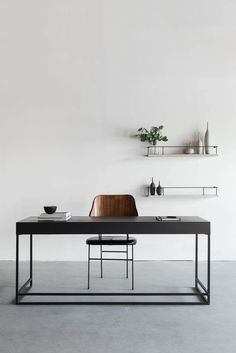 a dining table with two chairs and shelves on the wall behind it in a white room