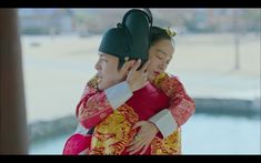 a man holding a woman on his back while they both wear traditional chinese clothing and headgear