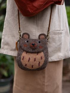 a woman is holding a brown bear purse